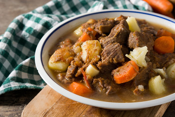 Irish beef stew with carrots and potatoes on wooden table