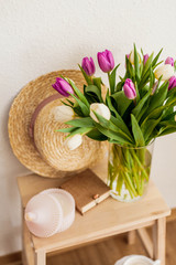 Women's things. Casket, women's straw hat, wicker bag, sweater, bouquet of tulips in a glass vase. Natural products. Cup of cappuccino.