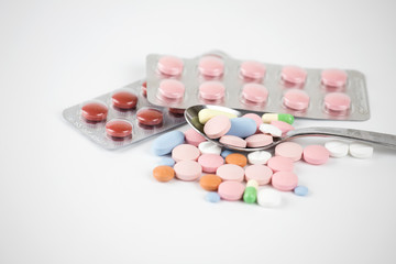 Multi-colored medical capsules, a spoonful of pills and capsules