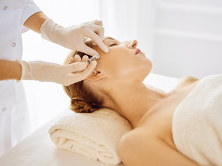Beautiful woman receiving beauty injections with closed eyes. Beautician doctor hands doing beauty procedure to female face with syringe. Cosmetic medicine and surgery concept