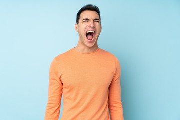 Fototapeta premium Young caucasian handsome man isolated on blue background shouting to the front with mouth wide open