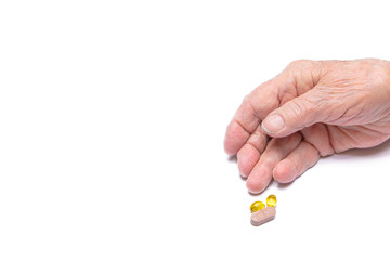 Close-up of an old woman's hand holding pills. White background.Concept of illness, flu, old age, Coronavirus
