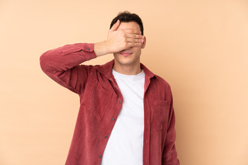 Young caucasian handsome man isolated on beige background covering eyes by hands. Do not want to...