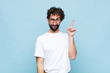 young bearded man with glasses against blue wall