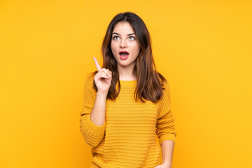 Young caucasian woman isolated on yellow background thinking an idea pointing the finger up