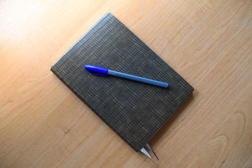 Notepad and pen on a light wooden table in the office.