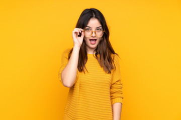 Young caucasian woman isolated on yellow background with glasses and surprised