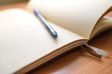 Notepad and pen on a light wooden table in the office.