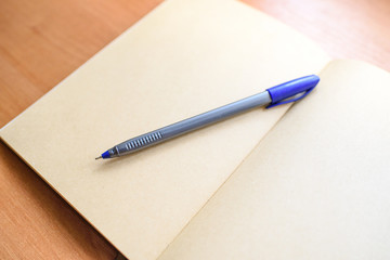 Notepad and pen on a light wooden table in the office.