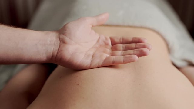 massage therapist applies oil to their hands before massage, closeup