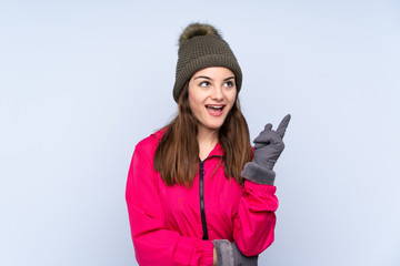 Young girl with winter hat isolated on blue background thinking an idea pointing the finger up