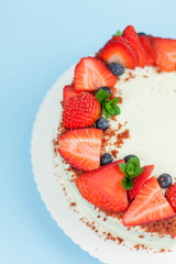 Close-up. Beautiful cake with berries with butter cream on a blue background. Cake with red cakes.