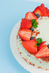 Close-up. Beautiful cake with berries with butter cream on a blue background. Cake with red cakes.
