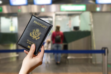 Woman hand holding american passport  in the airport opposite Immigration and passport control....
