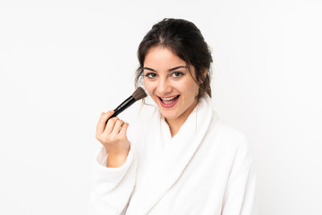 Young caucasian woman isolated on white background holding makeup brush and surprised