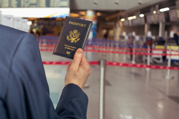Man (businessman)  in a blue suit holding american passport on the airport escalator