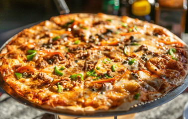 Close-up large round fresh tasty seafood pizza with capers and olives served on a round pizza stand. View from above