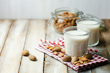 Fresh organic vegan almond milk. Alternative source of protein for vegetarians. Raw almonds as ingredients, peeled and unpeeled. Concept of healthy lifestyle. Closeup, wooden background, copy space