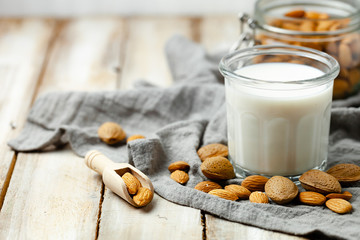 Fresh organic vegan almond milk. Alternative source of protein for vegetarians. Raw almonds, peeled and unpeeled to illustrate ingredients. Concept of healthy lifestyle. Closeup, white background
