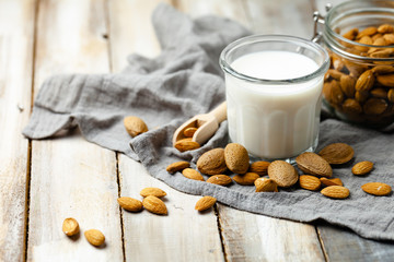 Fresh organic vegan almond milk. Alternative source of protein for vegetarians. Raw almonds, peeled and unpeeled to illustrate ingredients. Concept of healthy lifestyle. Closeup, white background