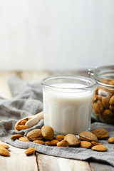 Fresh organic vegan almond milk. Alternative source of protein for vegetarians. Raw almonds, peeled and unpeeled to illustrate ingredients. Concept of healthy lifestyle. Closeup, white background