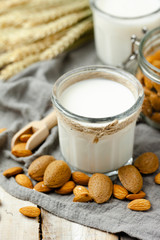 Fresh vegan alternative milk in big glass. Closeup, wooden background. Healthy vegetarian food concept, delicious low calorie drink. Almond, hazelnut, oatmeal, rice to illustrate raw ingredients. 
