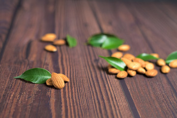 almonds on a wooden background with green leaves close-up. space for text . vegetarian organic diet