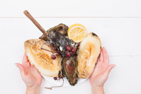 Woman Holds A Plate With Rotten Fruits, In Which A Knife Is Stuck, Stop Wasting Food Concept, Eating Stale Food.