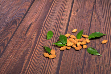 almonds on a wooden background with green leaves close-up. space for text . vegetarian organic diet