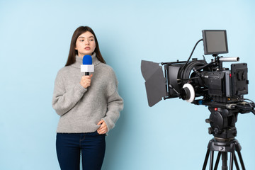 Reporter woman holding a microphone and reporting news over isolated blue background