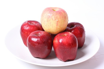 Apples with water drops on white plate
