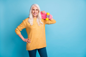 Portrait of her she nice-looking attractive lovely pretty charming modern cheerful cheery grey-haired woman carrying pink skate board isolated on bright vivid shine vibrant blue color background