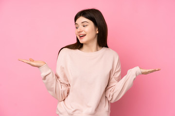 Young Ukrainian teenager girl over isolated pink background holding copyspace with two hands