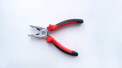 Steel pliers with a red-black handle are in the open state on a white background. Repair tool.