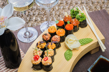 Set of several different rolls on a wooden stand on a table in a Japanese restaurant. Japanese traditional sushi and rolls.