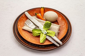 Easter table setting on textured white putty background. Spring holiday card template. Cutlery,...