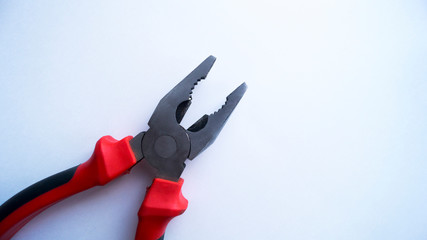 Steel pliers with a red-black handle are in the open state on a white background. Repair tool.