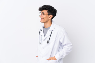Fototapeta premium Young Argentinian man over isolated white background wearing a doctor gown and with stethoscope