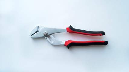 Obraz premium A removable steel key with a red-black handle lies in the closed state on a white background. Repair tool.