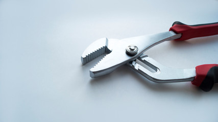 A adjustable steel key with a red-black handle lies in the open state on a white background.  Repair tool.