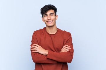 Young Argentinian man over isolated blue background keeping the arms crossed in frontal position