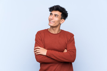 Fototapeta premium Young Argentinian man over isolated blue background looking up while smiling