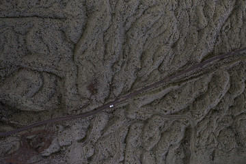 Aerial view of road and tiny white car among lava fields covered by moss
