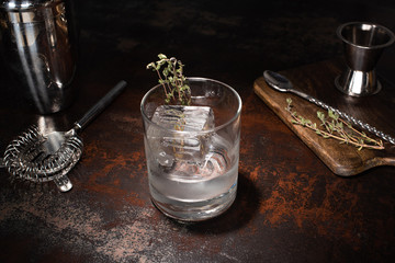 transparent glass with herb, ice cube and vodka on weathered surface