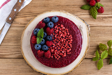 Raw dessert. Cake with berries on a wooden background. Raspberries and blackcurrants.