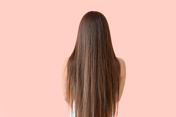 Beautiful woman with healthy long hair on color background, back view