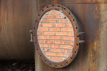 Closed metal tank with brick wall