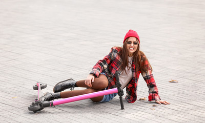 Young woman fallen off his kick scooter outdoors