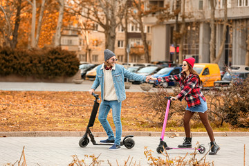 Young couple riding kick scooters outdoors © Pixel-Shot