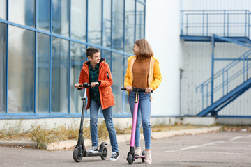 Active teenagers riding kick scooters outdoors